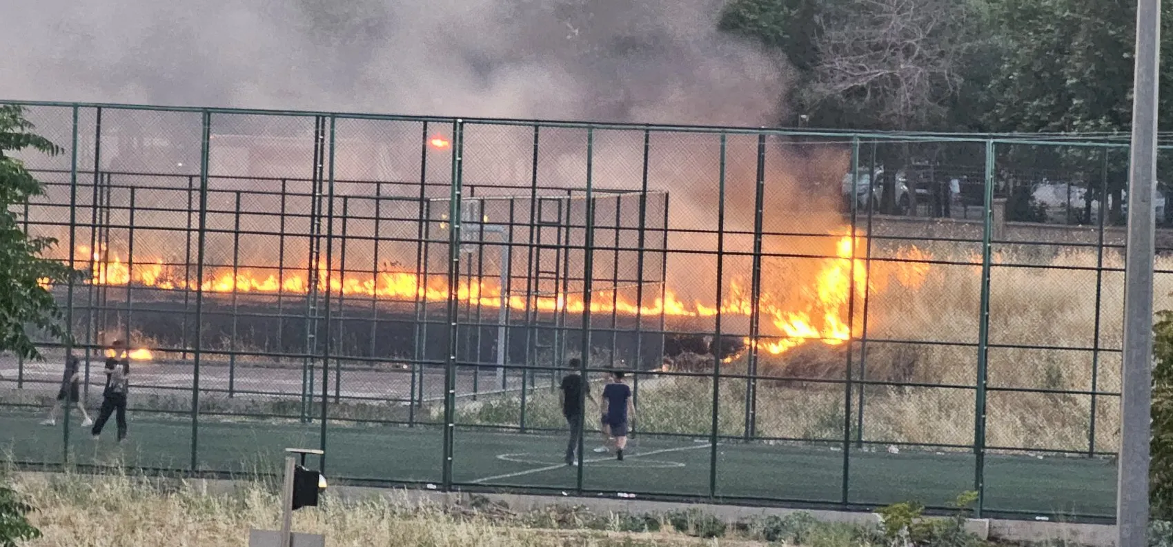 Bağlar'da otluk alanda yükselen alevlere aldırış etmediler Çocuklar maçlarına devam etti